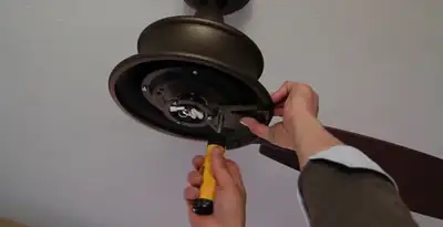 Electrician installing ceiling fan mounting bracket and fixture in Detroit, MI