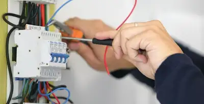 Electrician installing and adjusting circuit breakers in an electrical panel in Detroit, MI