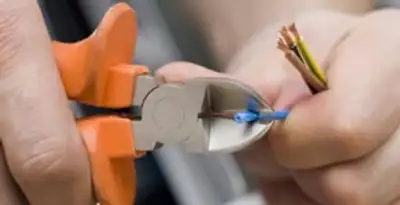 licensed electrician performing precise wire cutting and preparation during electrical service in Detroit, MI