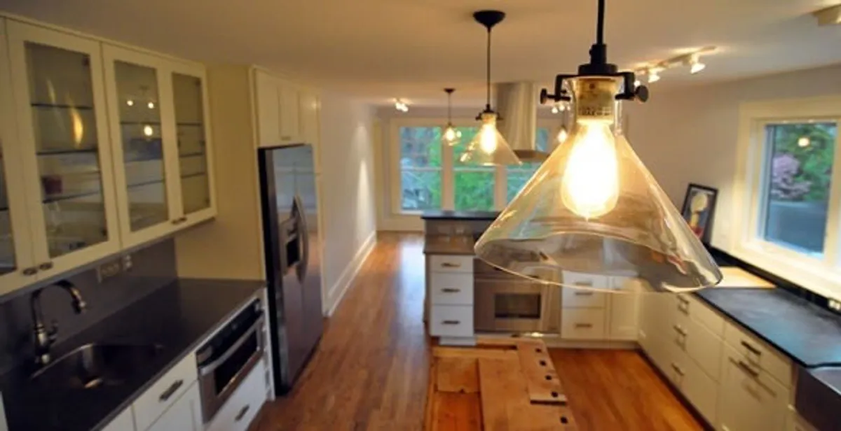 Residential electrician installing modern indoor light fixture in a home in Detroit, MI