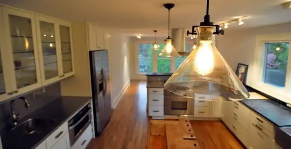 Residential electrician installing modern indoor light fixture in a home in Detroit, MI
