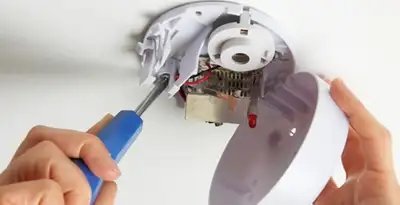 Certified technician wiring smoke detector during installation in Detroit, MI
